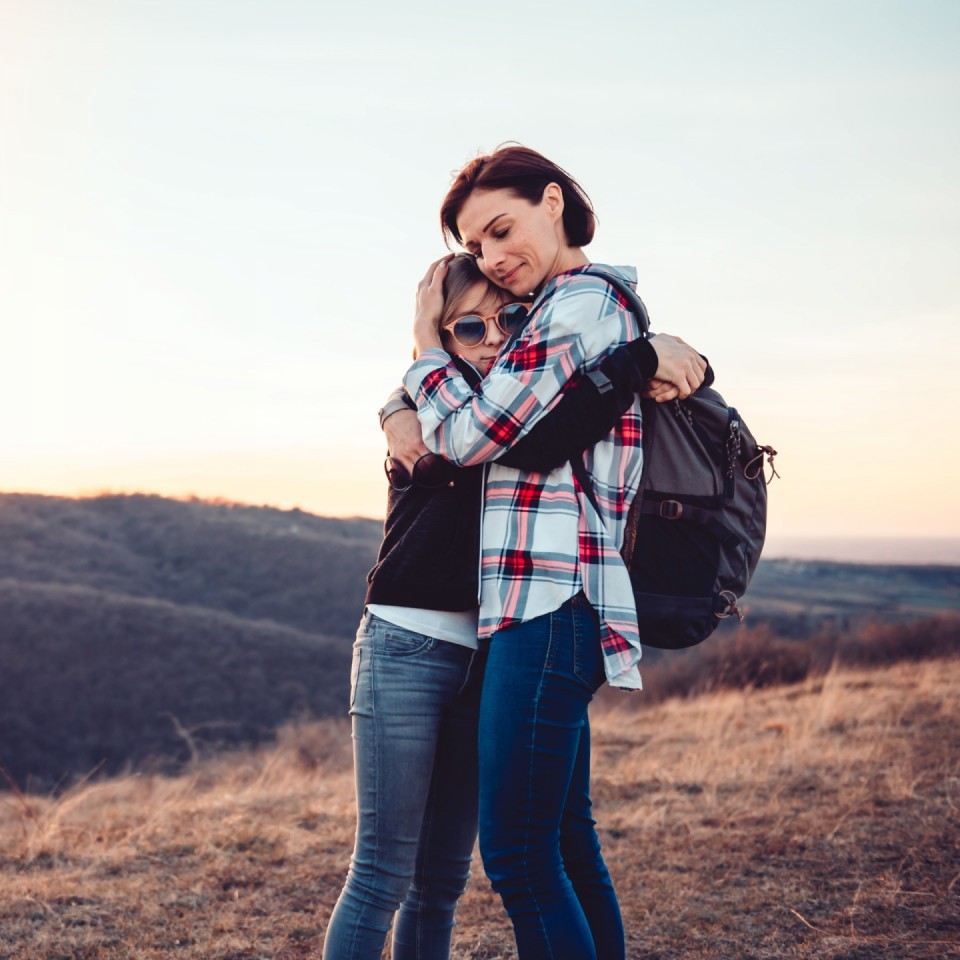 Mom and daughter hugging on a hill