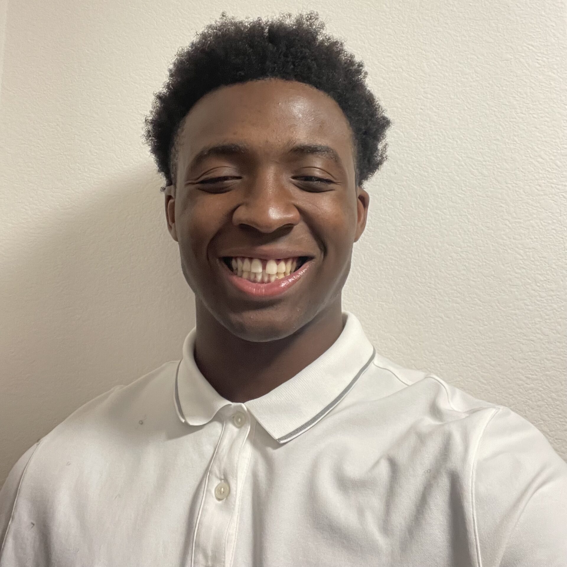 Smiling person wearing a white collared shirt against a plain background.